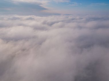 Bir dron kabarık bulutların üzerinde uçar. İnsansız hava aracı bulutların arasında uçuyor, merak ve korku hissi yaratıyor..