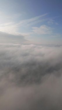 Bir dron kabarık bulutların üzerinde uçar. İnsansız hava aracı bulutların arasında uçuyor, merak ve korku hissi yaratıyor..