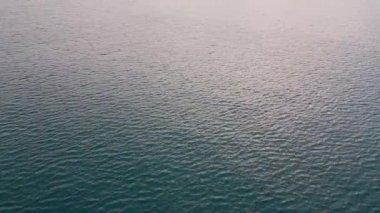 Gökyüzü arkaplanını yansıtan deniz yüzeyinin hava görüntüsü.
