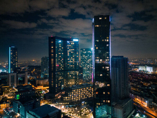 Istanbuls glass and concrete skyscrapers, home to offices, hotels, and residential complexes at night. Aerial drone view.