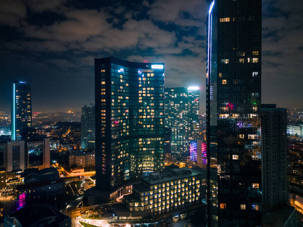 Istanbuls glass and concrete skyscrapers, home to offices, hotels, and residential complexes at night. Aerial drone view.