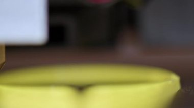 3D yazıcı, sarı plastikten yapılmış bir parça yazdırıyor, yakın plan görünüm.