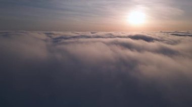 Uçsuz bucaksız kabarık bulutların üzerinde yükselen güneşin sakin bir drone görüntüsü..