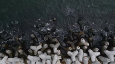 Kumlu bir plaja bir sıra beton silindir yerleştirilmiş..