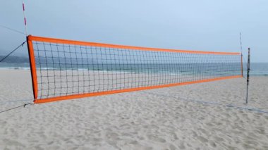 Okyanus kenarında kumlu bir plaja kurulmuş voleybol ağı güneşli gökyüzünün altında maça hazır..
