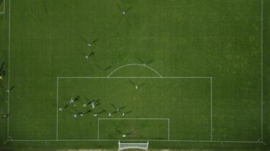 Futbol sahasını yukarıdan, oyuncular hareket ederken ve bir oyun sırasında pas atarken izle.
