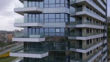 Güneş ışığını yansıtan sayısız pencereyle süslenmiş yüksek bir yapının görüntüsü..