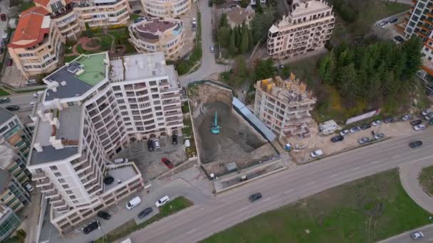 ブルドーザーは 都市の真ん中に別の建物の建設のためのピットを掘っています 空中ビュー — ストック動画