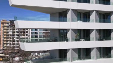 Güneş ışığını yansıtan sayısız pencereyle süslenmiş yüksek bir yapının görüntüsü..