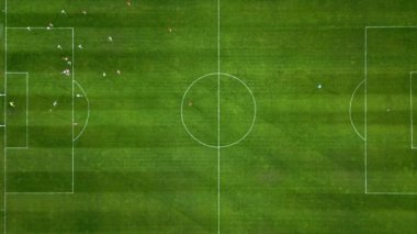 Futbol sahasının havadan görünüşü, oyuncular koşuyor, pas veriyor ve gol atıyor.