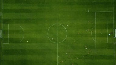 Futbol sahasının havadan görünüşü, oyuncular koşuyor, pas veriyor ve gol atıyor.