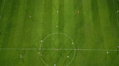 Futbol sahasının havadan görünüşü, oyuncular koşuyor, pas veriyor ve gol atıyor.