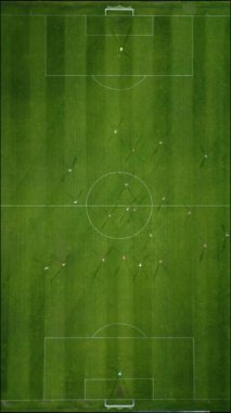 Futbol sahasının havadan görünüşü, oyuncular koşuyor, pas veriyor ve gol atıyor.