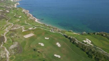 Okyanusun zeminine karşı kurulmuş bir golf sahasını keşfedin, yukarıdan yemyeşil manzarayı yakalayın..