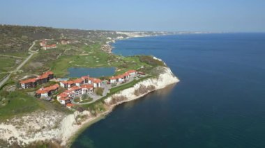Okyanus yakınlarındaki bir golf sahasının kuş bakışı manzarasını inceleyin. Suyun arka planındaki yemyeşil çimenleri gösterin..