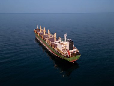 Büyük bir kargo gemisi büyük bir su kütlesi üzerinde zarifçe süzülüyor, büyüklüğünü ve gücünü gösteriyor..