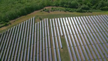 Yaz boyunca bir ormanın yanındaki güneş enerjisi istasyonunun drone görüntüsü. Yenilenebilir enerji, doğayla çarpışır..