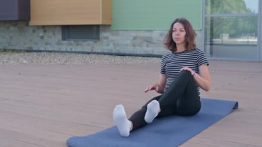 Genç bir kadın, ahşap bir zeminde yoga yapıyor..