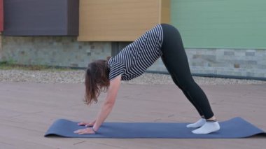 Genç bir kadın, ahşap bir zeminde yoga yapıyor..