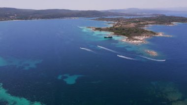 Turkuaz suları, kumlu plajları ve Yunanistan 'ın Sithonia kentinde küçük bir adaya demir atmış bir yelkenli gemisinin bulunduğu kıyı manzarası bir yaz kaçamağının güzelliğini ve macerasını yakalıyor..