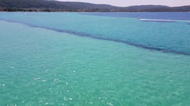 Sakin, koyu mavi okyanusta hızla ilerleyen bir teknenin havadan görünüşü ardında beyaz dalgalar bırakıyor. Uçsuz bucaksız denizin basitliği ve sükuneti teknelerin hareketleriyle tezat oluşturuyor..