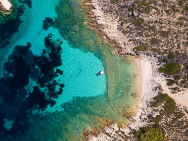 Yunanistan 'ın Sithonia kentinde kristal berrak turkuvaz suları, kayalık kıyı şeridi ve kıyıya demir atmış küçük bir tekneyle Akdeniz' in el değmemiş güzelliğini yakalayan tenha bir koy manzarası..