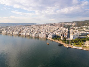 Yunanistan 'ın Selanik kentinin havadan görünüşü, kıyı şeridi boyunca yoğun binalarıyla kenti, dağların ve mavi denizin zeminine karşı göstererek kenti gösteriyor.