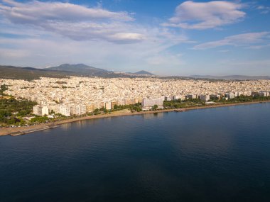 Yunanistan 'ın Selanik kentinin havadan görünüşü, kıyı şeridi boyunca yoğun binalarıyla kenti, dağların ve mavi denizin zeminine karşı göstererek kenti gösteriyor.