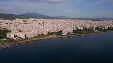 Yunanistan 'ın Selanik kentinin havadan görünüşü, kıyı şeridi boyunca yoğun binalarıyla kenti, dağların ve mavi denizin zeminine karşı göstererek kenti gösteriyor.