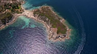 Yunanistan 'ın Sithonia Yarımadası' nda kristal berrak sularla çevrili plajları ve kayaları olan bir adanın havadan görünüşü. Yatlar ve tekneler turkuaz sularda demirliyor. Yakındaki adalar ve resifler görülebilir..