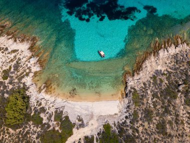 Yunanistan 'ın Sithonia kentinde kristal berrak turkuvaz suları, kayalık kıyı şeridi ve kıyıya demir atmış küçük bir tekneyle Akdeniz' in el değmemiş güzelliğini yakalayan tenha bir koy manzarası..