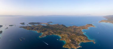 Yunanistan 'ın Sithonia, Diaporos adasının büyüleyici kıyı şeridinin panoramik hava manzarası, turkuaz körfezler, yemyeşil alanlar ve derin mavi denizde dağınık adalar, nefes kesici güzelliği yakalıyor.
