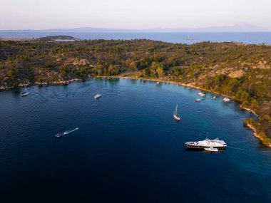 Yunanistan 'ın Sithonia kentinde kıyı boyunca kenetlenmiş çeşitli tekne ve yatlarla dolu canlı bir marinanın havadan görünüşü, bir kıyı limanının canlı ve manzaralı atmosferini yakalıyor..
