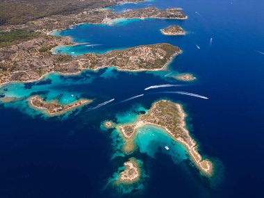 Yunanistan 'ın Sithonia Yarımadası' nda kristal berrak sularla çevrili plajları ve kayaları olan bir adanın havadan görünüşü. Yatlar ve tekneler turkuaz sularda demirliyor. Yakındaki adalar ve resifler görülebilir..
