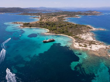 Turkuaz suları, kumlu plajları ve Yunanistan 'ın Sithonia kentinde küçük bir adaya demir atmış bir yelkenli gemisinin bulunduğu kıyı manzarası bir yaz kaçamağının güzelliğini ve macerasını yakalıyor..