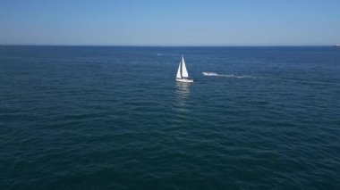 Sakin, mavi sularda, berrak bir gökyüzünün altında süzülen sakin bir yelkenli. Uzak gemiler ve yelkenliler ufukta belirdi. Huzurlu bir deniz manzarası yarattılar..