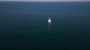 Sakin, mavi sularda, berrak bir gökyüzünün altında süzülen sakin bir yelkenli. Uzak gemiler ve yelkenliler ufukta belirdi. Huzurlu bir deniz manzarası yarattılar..