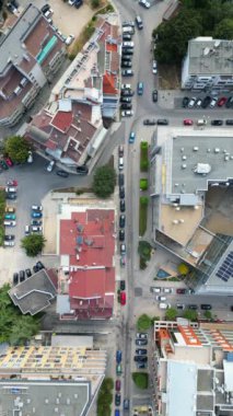 İkametgah binaları, yeşil alanları ve park etmiş araçları olan bir şehir bloğu. Görüntü, yukarıdaki kentsel yaşamın organize yapısını ve yoğunluğunu yakalar..