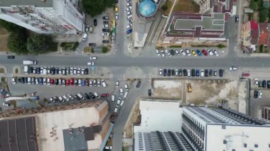 İkametgah binaları, yeşil alanları ve park etmiş araçları olan bir şehir bloğu. Görüntü, yukarıdaki kentsel yaşamın organize yapısını ve yoğunluğunu yakalar..