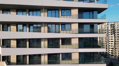 Benzersiz, sendelemiş balkonları olan modern bir konut kulesinin insansız hava aracı uçuşu. Video, binaların yenilikçi tasarımı ve hareketli kentsel çevre içindeki konumunu vurguluyor.