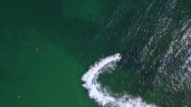 Zümrüt yeşili suda yüksek hızlı dönüşleri yakalayan jet ski yarışlarının hava görüntüleri. Dinamik aksiyon, rekabetçi su sporlarının heyecan ve adrenalinini gözler önüne seriyor..