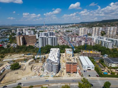 Şehir manzarası, devam eden inşaat projeleri ve tamamlanmış konut binaları. Fotoğraf kentsel kalkınma, genişleme ve modern altyapının büyümesini vurguluyor.