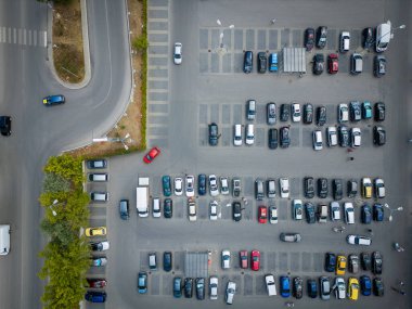 Kalabalık bir kavşakta, arabalarla dolu, iyi organize edilmiş bir otoparkın havadan görüntüsü. Fotoğraf, kentsel yaşamın yapılandırılmış düzenini ve günlük akışını vurguluyor.