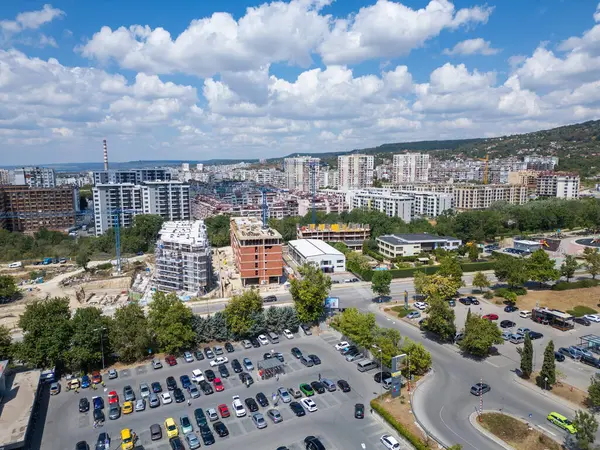 Devam eden inşaatı, modern konut binaları ve kalabalık bir otoparkı olan büyüyen şehir merkezinin havadan görüntüsü. Görüntü şehrin dinamik genişlemesini ve gelişimini yakalar..