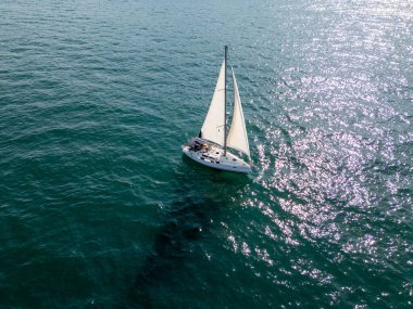 Sakin, mavi sularda, berrak bir gökyüzünün altında süzülen sakin bir yelkenli. Uzak gemiler ve yelkenliler ufukta belirdi. Huzurlu bir deniz manzarası yarattılar..