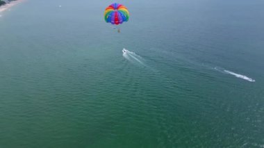 Aşağıdaki bir sürat teknesi tarafından çekilen, açık denizde süzülen renkli bir deniz paraşütünün insansız hava aracı videosu. Uçsuz bucaksız, sakin deniz manzarasına karşı paraşütle atlamanın heyecanını ve özgürlüğünü yakalıyor..