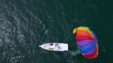 Bir sürat teknesi tarafından çekilen renkli bir deniz paraşütünün drone videosu. Sahne deniz paraşütünün heyecanını yakalıyor. Kıyı şeridi ve açık denizin çarpıcı manzarası..