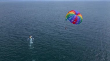 Aşağıdaki bir sürat teknesi tarafından çekilen, açık denizde süzülen renkli bir deniz paraşütünün insansız hava aracı videosu. Uçsuz bucaksız, sakin deniz manzarasına karşı paraşütle atlamanın heyecanını ve özgürlüğünü yakalıyor..