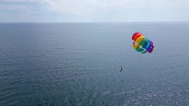Aşağıdaki bir sürat teknesi tarafından çekilen, açık denizde süzülen renkli bir deniz paraşütünün insansız hava aracı videosu. Uçsuz bucaksız, sakin deniz manzarasına karşı paraşütle atlamanın heyecanını ve özgürlüğünü yakalıyor..
