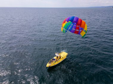 Aşağıdaki bir sürat teknesi tarafından çekilen, açık denizde süzülen renkli bir deniz paraşütünün insansız hava aracı videosu. Uçsuz bucaksız, sakin deniz manzarasına karşı paraşütle atlamanın heyecanını ve özgürlüğünü yakalıyor..